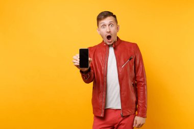 Portre vogue eğlenceli genç adam kırmızı deri ceket, t-shirt ile parlak sarı arka plan üzerinde izole boş boş perde hareket eden telefon tutun. İnsanlar samimi duygular yaşam tarzı kavramı. Reklam alanı