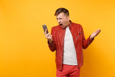 Portre vogue kızgın üzgün genç adam cep telefonu parlak sarı eğilimleri arka plan üzerinde izole kırmızı deri ceket t-shirt konuşma içinde çığlık. İnsanlar samimi duygular yaşam tarzı kavramı. Reklam alanı