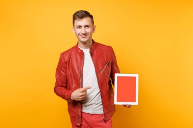 Parlak sarı zemin üzerine kırmızı deri ceket t-shirt tutun tablet pc defterinde boş boş ekran ile genç adam izole portre vogue eğlenceli. İnsanlar samimi duygular yaşam tarzı kavramı. Reklam alanı