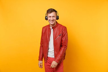 Portre vogue mutlu eğlenceli genç adam kırmızı deri ceket, t-shirt üzerinde arka plan parlak sarı eğilimleri izole kulaklık müzik dinlemek. İnsanlar samimi duygular yaşam tarzı kavramı. Reklam alanı