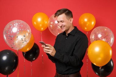 Genç adam tipik SMS haber kırmızı arka plan hava balonu üzerinde tutarak, cep telefonuyla siyah klasik gömlek gülümseyen. Dünya Kadınlar Günü mutlu yeni yıl Doğum günü mockup tatil parti konsept