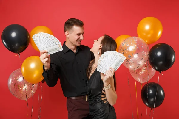 夫妇在黑色的衣服庆祝生日聚会 持有现金钱孤立在明亮的红色背景热气球 情人节国际妇女节新年快乐2019概念 — 图库照片