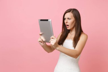 Şok şaşkın gelin kadın beyaz düğün elbise çalışma tablet pc bilgisayar, pastel pembe arka plan üzerinde izole görüntülü görüşme yapma. Yapılacaklar listesi düğün. Kutlama organizasyonu. Kopya alanı
