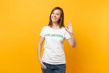 Mutlu gülümseyerek portresi beyaz t-shirt ile yazılı yazıt yeşil başlık gönüllü üzerinde sarı arka plan izole kadın memnun. Gönüllü ücretsiz destek yardım, sadaka grace iş kavramı