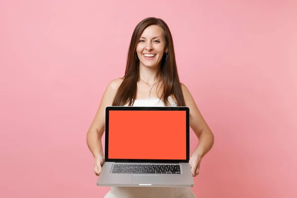 Portrait of joyful bride woman in wedding dress hold laptop pc computer with blank black empty screen isolated on pastel pink background. Wedding to do list. Organization of celebration. Copy space