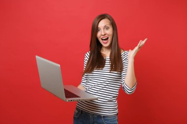 Ağız geniş açık tutarak, sürpriz, arayan genç kadın kırmızı zemin üzerine izole dizüstü pc bilgisayar üzerinde çalışan eller yayılan heyecanlı. İnsanlar samimi duygular yaşam tarzı kavramı. Kopyalama alanı alay