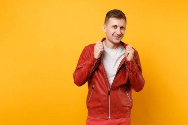 Portrait vogue confident handsome young man 25-30 years in red leather jacket, t-shirt stand isolated on bright trending yellow background. People sincere emotions lifestyle concept. Advertising area clipart