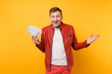 Portre vogue yakışıklı genç adam kırmızı deri ceket, t-shirt holding dolarlık banknot bir sürü nakit para üzerinde parlak gidişli sarı arka plan izole. İnsanlar yaşam tarzı kavramı. Reklam alanı
