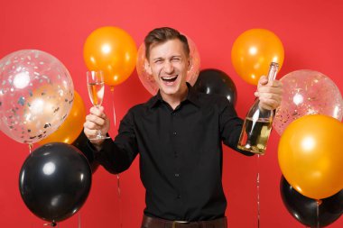 Şişe, bardak şampanya kırmızı arka plan hava balonu üzerinde tutarak siyah klasik gömlek genç adam gülüyor. Sevgililer Dünya Kadınlar Günü mutlu yeni yıl Doğum günü mockup tatil parti konsept