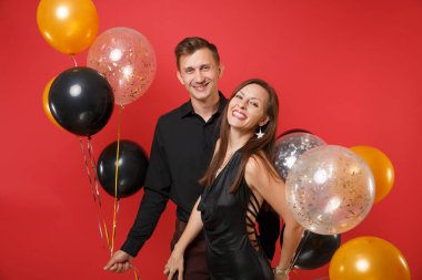 Parlak kırmızı arka plan hava balonu üzerinde kutluyor Doğum günü tatil partisi izole siyah giysili genç çift çarpıcı. St. Valentine's Dünya Kadınlar Günü mutlu yeni yıl 2019 kavramı.