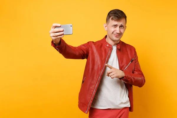 肖像英俊的年轻男子穿着红色的皮夹克 T恤衫做自拍在手机上被隔绝在明亮的趋势黄色背景上 人们真挚的情感生活理念 广告专区 — 图库照片
