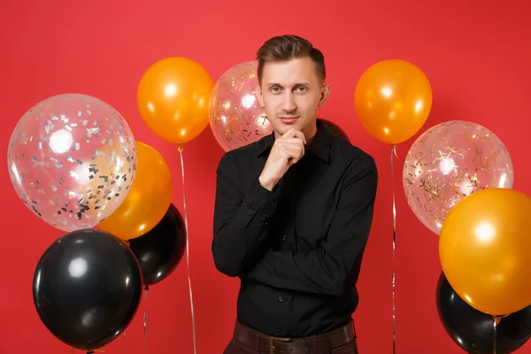 Joven Sonriente Camisa Clásica Negra Manteniendo Mano Barbilla Celebrando Globos —  Fotos de Stock