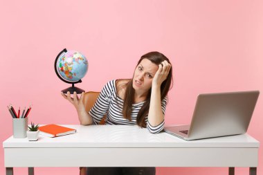 Tahriş olmuş kadın yandan eğilerek sit planlama tatil having problem ile dünya tutarak, pastel pembe arka plan üzerinde izole dizüstü ofiste çalışmak. Başarı iş kariyer. Kopya alanı