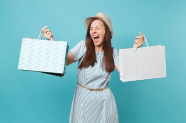 Portre sonra alışveriş izole mavi pastel arka plan üzerinde elbise, hasır şapka paketleri çanta ile tutarak satın alan yaz aylarında gülümseyen güzel beyaz kadın heyecan. Kopya alanı reklam için
