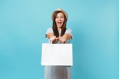 Portre sonra alışveriş izole mavi pastel arka plan üzerinde elbise, hasır şapka paketleri çanta ile tutarak satın alan yaz aylarında gülümseyen güzel beyaz kadın heyecan. Kopya alanı reklam için