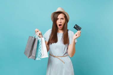 Yazlık elbise, hasır şapka paketleri çanta alışveriş sonra satın almalarla tutan üzgün üzgün çığlık atan kadın portresi banka kredi kartı üzerinde mavi pastel renkli izole. Kopya alanı reklam için
