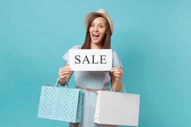 Yaz elbiseli kadın portre, hasır şapka holding çanta alışveriş sonra satın almalarla paketleri, boş söz bulut, pastel mavi arka plan üzerinde izole konuşma balonu kartı boş. Kopyalama alanı reklam.