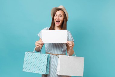 Yaz elbiseli kadın portre, hasır şapka holding çanta alışveriş sonra satın almalarla paketleri, boş söz bulut, pastel mavi arka plan üzerinde izole konuşma balonu kartı boş. Kopyalama alanı reklam.