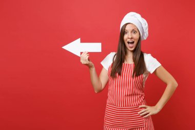 Ev hanımı kadın şef aşçı ya da baker izole kırmızı duvar arka plan üzerinde çizgili önlük, beyaz tişört, toque şefler şapkalı. Eğlence gülümseyen tarafı ok ile gösterilen temizlikçi kadın. Kopyalama alanı kavramı alay