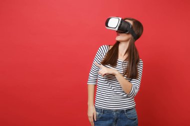 Genç kadın rahat çizgili kıyafetler sanal gerçeklik bardaklarda işaret parmağı bir kenara parlak kırmızı duvar arka plan üzerinde izole arıyorum. İnsanlar samimi duygular yaşam tarzı kavramı. Kopyalama alanı alay