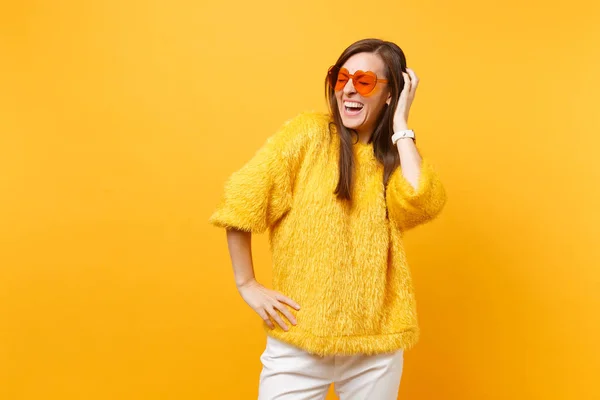 在毛皮毛衣和心脏橙色眼镜的闭着眼睛的笑年轻妇女把手在明亮的黄色背景查出的头 人们真挚的情感 生活方式的概念 广告专区 — 图库照片