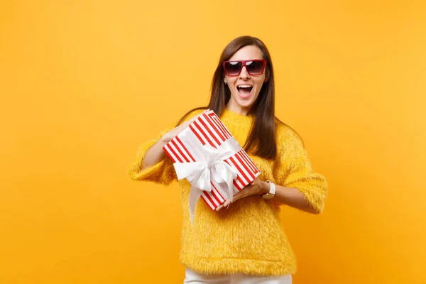赤い眼鏡を祝って 明るい黄色の背景に分離された休日を楽しんでプレゼント ギフト赤箱を持って興奮している女性 の心から感情 ライフ スタイルのコンセプト 広告エリア — ストック写真