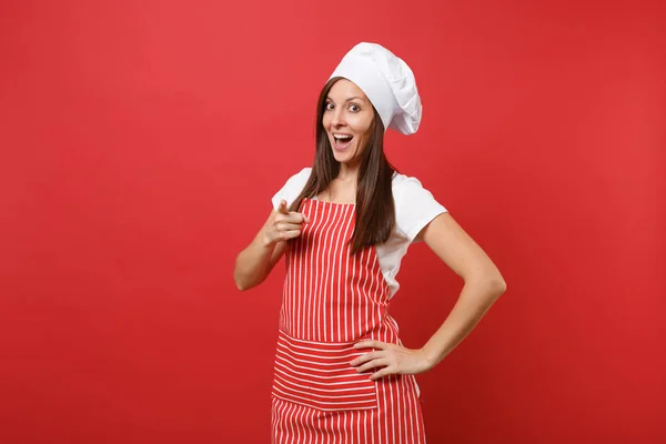 家庭主妇女厨师或面包师在条纹围裙 扭矩厨师帽查出的红色墙壁背景 漂亮的女管家指着照相机的手指 模拟复制空间概念 — 图库照片