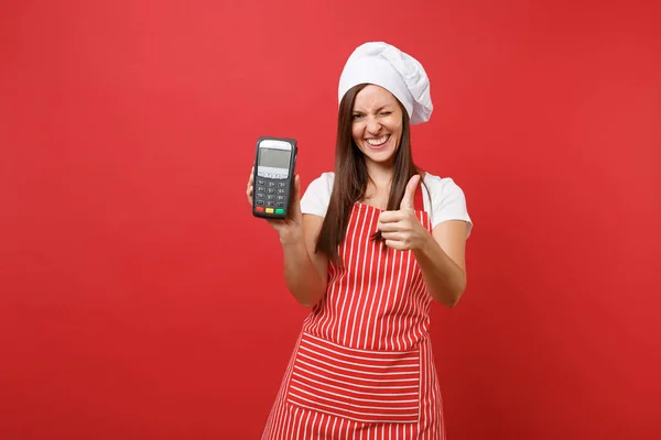Housewife female chef cook or baker in striped apron t-shirt toque chefs hat isolated on red wall background. Woman hold in hand wireless bank payment terminal nfc device. Mock up copy space concept