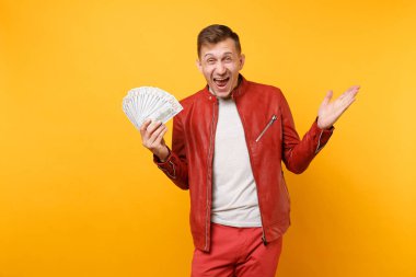 Portre vogue yakışıklı genç adam kırmızı deri ceket, t-shirt holding dolarlık banknot bir sürü nakit para üzerinde parlak gidişli sarı arka plan izole. İnsanlar yaşam tarzı kavramı. Reklam alanı
