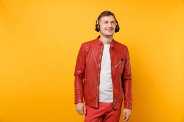 Portre vogue mutlu eğlenceli genç adam kırmızı deri ceket, t-shirt üzerinde arka plan parlak sarı eğilimleri izole kulaklık müzik dinlemek. İnsanlar samimi duygular yaşam tarzı kavramı. Reklam alanı