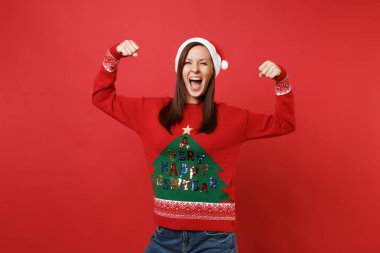 Neşeli güçlü genç Noel Baba kız kazaklı, kırmızı duvar arka plan üzerinde Noel şapka çığlık pazı, gösterilen kasları izole. Mutlu yeni yıl 2019 kutlama tatil parti kavramı. Kopyalama alanı alay