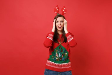 Örme kazak, dekoratif geyik boynuzları kırmızı zemin üzerine izole kafasına koyarak eller eğlence genç Noel Baba kız çapraşık. Mutlu yeni yıl 2019 kutlama tatil parti kavramı. Kopyalama alanı alay