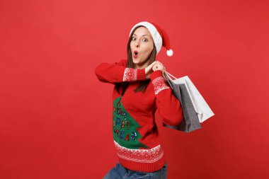 Alışveriş izole kırmızı zemin üzerine sonra ağız tutan sürpriz arıyor açık tutmak hayran genç Noel Baba kız çanta satın almalarla paketler. Mutlu yeni yıl 2019 kutlama tatil parti konsept