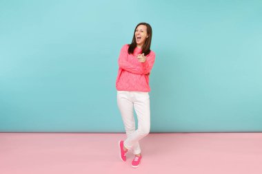 Tam uzunlukta örme gül kazaklı gülümseyen genç kadın portresi, beyaz parlak pembe mavi pastel duvar arka planda Studio izole poz pantolon. Moda yaşam tarzı kavramı. Kopyalama alanı alay