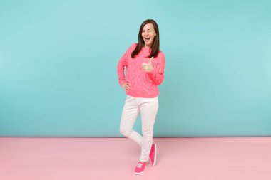 Tam uzunlukta örme gül kazaklı gülümseyen genç kadın portresi, beyaz parlak pembe mavi pastel duvar arka planda Studio izole poz pantolon. Moda yaşam tarzı kavramı. Kopyalama alanı alay