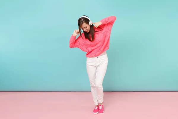在针织玫瑰毛衣 白色裤子 在明亮的粉红色蓝色柔和的墙壁背景在演播室的耳机查出的幸福的年轻妇女的全长肖像 时尚生活理念 模拟复制空间 — 图库照片
