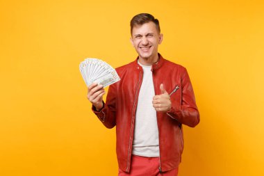 Portre vogue yakışıklı genç adam kırmızı deri ceket, t-shirt holding dolarlık banknot bir sürü nakit para üzerinde parlak gidişli sarı arka plan izole. İnsanlar yaşam tarzı kavramı. Reklam alanı