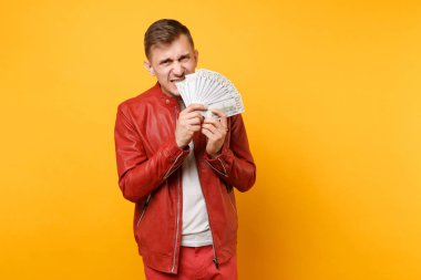 Portre vogue kırmızı deri ceket, t-shirt kızgın genç adam eğlenceli bir dolarlık banknot bir sürü holding, nakit para üzerinde parlak gidişli sarı arka plan izole. İnsanlar yaşam tarzı kavramı. Reklam alanı