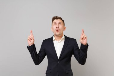 Parmak çarpı işareti, ayak uydurarak seyir klasik siyah elbiseli Genç iş adamı Studio gri arka plan üzerinde izole dilek yapma yalvaran. Başarı kariyer servet iş kavramı. Kopyalama alanı alay