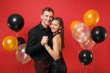 Parlak kırmızı arka plan hava balonu üzerinde kutluyor Doğum günü tatil partisi izole siyah giysili genç çift çarpıcı. St. Valentine's Dünya Kadınlar Günü mutlu yeni yıl 2019 kavramı.