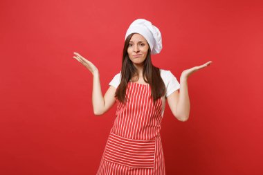 Ev hanımı kadın şef aşçı ya da baker izole kırmızı duvar arka plan üzerinde çizgili önlük, beyaz tişört, toque şefler şapkalı. Güzel çapraşık kahya kadın eller yayılıyor. Kopyalama alanı kavramı alay