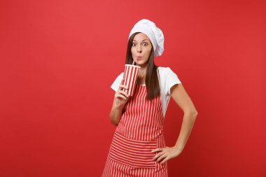 Ev hanımı kadın şef aşçı ya da baker izole kırmızı duvar arka plan üzerinde çizgili önlük, beyaz tişört, toque şefler şapkalı. Güzel hizmetçi kadın plastik bardak gazoz cola tutun. Kopyalama alanı kavramı alay