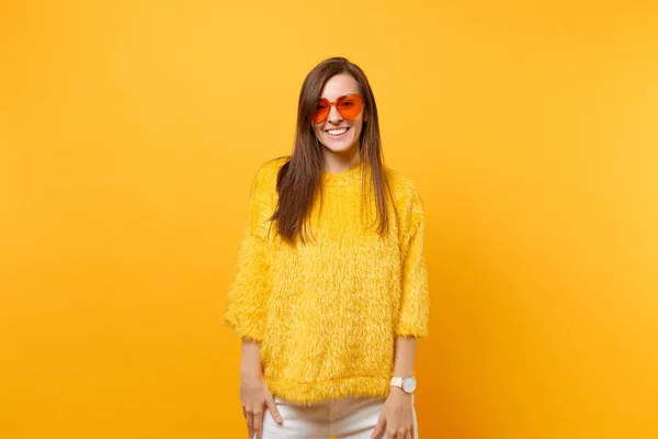 肖像的微笑美丽开朗的年轻女子在毛皮毛衣和心脏橙色眼镜站在明亮的黄色背景隔绝 人们真挚的情感生活理念 广告专区 — 图库照片