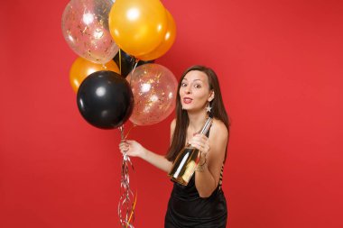 Siyah elbise kırmızı zemin üzerine izole şampanya hava balonları şişe tutan kutlayarak oldukça neşeli genç kız. Dünya Kadınlar Günü mutlu yeni yıl Doğum günü mockup tatil parti konsept