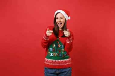 Örme kazak, yanıp sönen, Noel şapka neşeli Noel Baba kız kamerada işaret parmakları işaret izole kırmızı zemin üzerine. Mutlu yeni yıl 2019 kutlama tatil parti kavramı. Kopyalama alanı alay