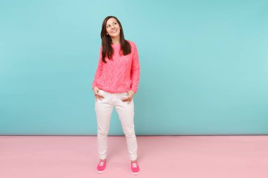 Tam uzunlukta örme gül kazaklı rüya gibi genç kadın portresi, beyaz parlak pembe mavi pastel duvar arka planda Studio izole poz pantolon. Moda yaşam tarzı kavramı. Kopyalama alanı alay