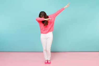 Tam uzunlukta örme gül kazaklı gülümseyen genç kadın portresi, beyaz parlak pembe mavi pastel duvar arka planda Studio izole poz pantolon. Moda yaşam tarzı kavramı. Kopyalama alanı alay