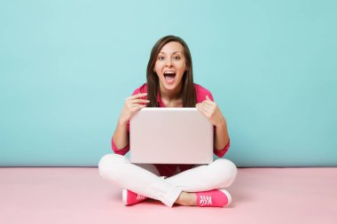 Gül gömlek bluz beyaz pantolon dizüstü pc kullanarak katta oturan genç kadın portresi tam uzunlukta pembe mavi pastel duvar arka plan studio izole. Moda yaşam tarzı kavramı alay kopya alanı