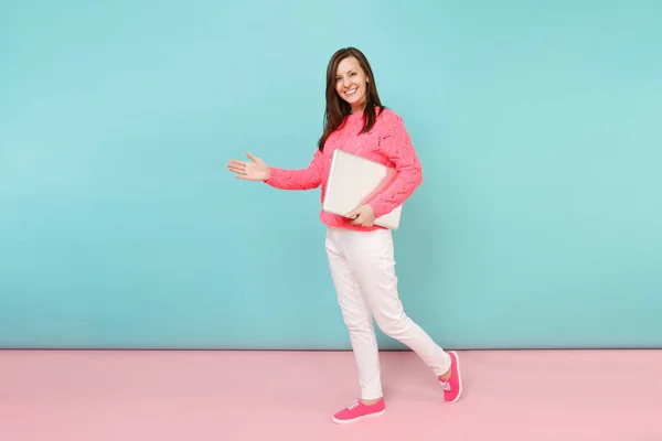 妇女的全长肖像针织玫瑰毛衣白色裤子持有膝上型电脑电脑查出明亮的粉红色蓝色蜡笔墙壁背景在工作室时尚生活方式概念模拟复制空间 — 图库照片