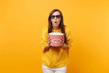 Şok korkmuş genç kız film film izlerken, kova patlamış mısır parlak sarı arka plan üzerinde izole tutan 3d IMAX gözlük. Sinema yaşam tarzı kavramı insanların samimi duygular. Reklam alanı